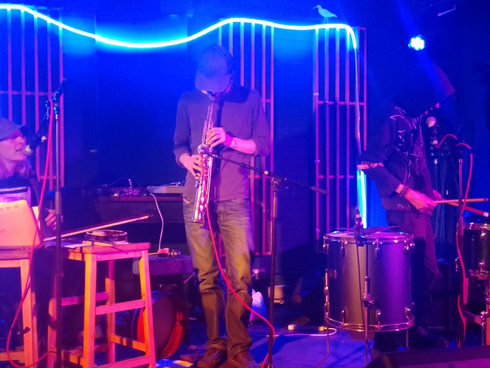 Triple Negative playing at Wharf Chambers, Leeds. 3 people on a small stage playing violin, sorprano saxophone and drums. It all looks slightly mysterious, non-rockist, not at all showbiz.