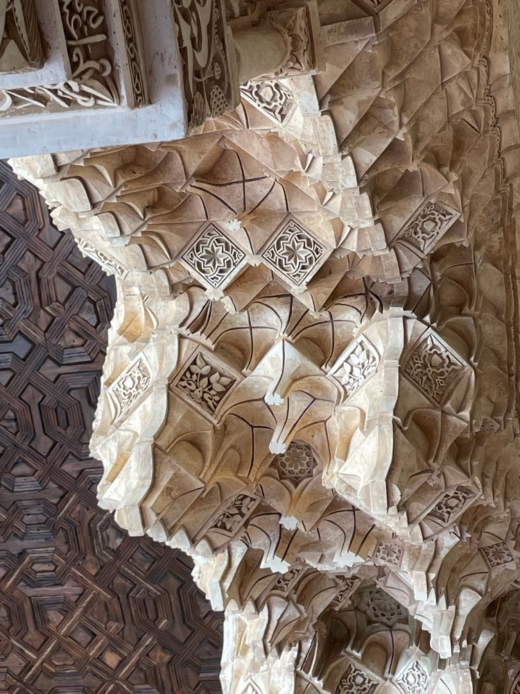 Detail of extraordinary pale coloured honeycomb plaster work in the Nazrid Palace of the Alhambra, with an equally remarkable carved dark wooden ceiling above it to the left.