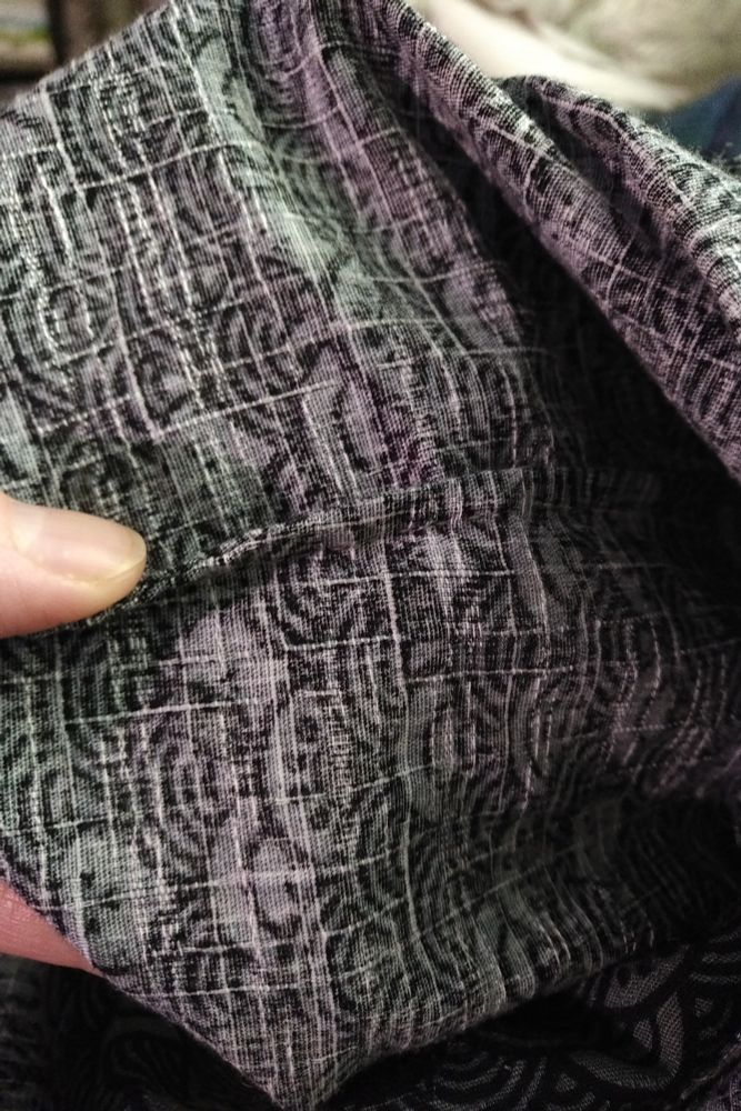 A french seam, on the inside.
The fabric's wrong side is a paler version of the printed pattern, with indistinct white gridlines from the woven fabric visible - the fabric is dobby - a textured weave that has thicker and thinner yarns.
The french seam is being held upright by my thumb so you can see the folded central seam edge where the raw edges are captured by another line of stitching, inside the seam. It's a really neat seam and helps prevent fraying of loosely-woven fabrics.
