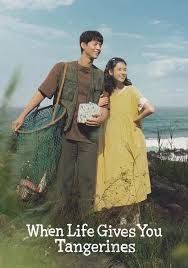 Promotional image for When Life Gives You Tangerines.
Two young Korean adults, posing as a couple. Park Bo-gum as a very tall, poor fisherman in brown t-shirt, tackle vest, and trousers, holding a green fishing net with some catch at the bottom. IU as a very pregnant young mother, smiling in a very large yellow dress. They're standing in the grass near the shoreline, with a black rock beach fading into the ocean waves behind them, under a blue sky with diffuse grey clouds.