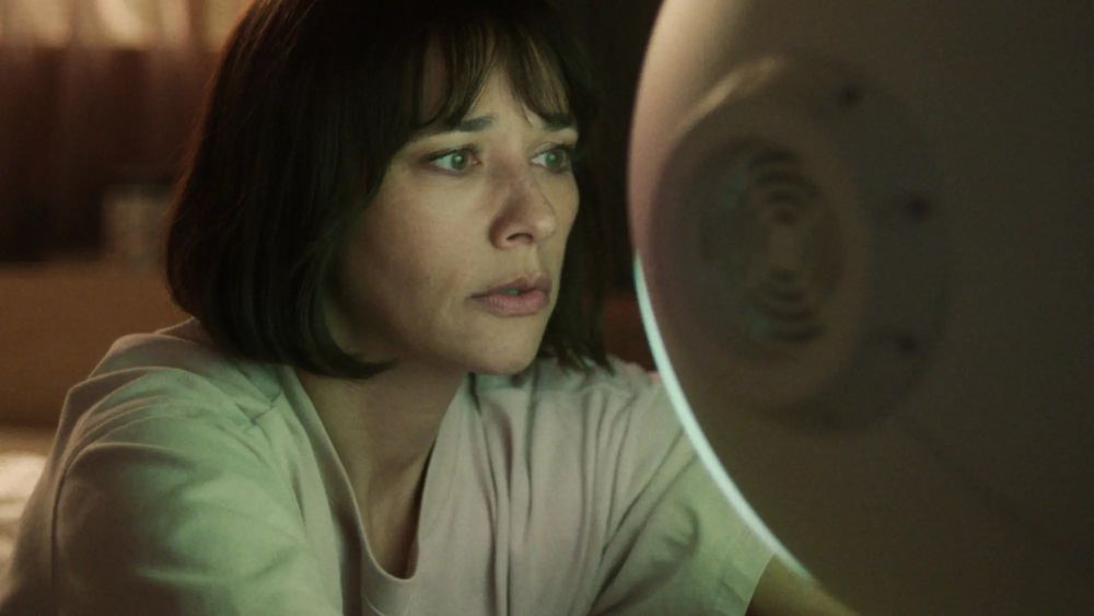 Rashida Jones as Suzie Sakamoto in Sunny.
A Black woman with a straight, chin-length bobbed haircut, wearing a pale t-shirt, stares concernedly into the glowing face of her personal robot (a large orb partially visible on the right side of the image, with a circular protrusion where an ear would be (but it's a fan).