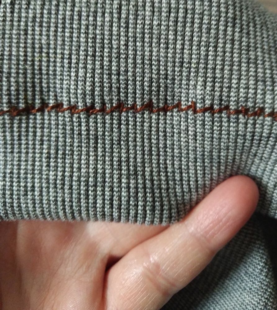 The front (outside) of the cross stitch - a lop-sided zigzag stitch. The stitch progresses with a diagonal line and a vertical line that creates almost right-angle triangles all in a row (just not closed).

The thread is a deep brown and the fabric is a marled pale grey. I'm going to dye it either dark grey or navy and the thread will also pick up enough dye to not stand out as brown.