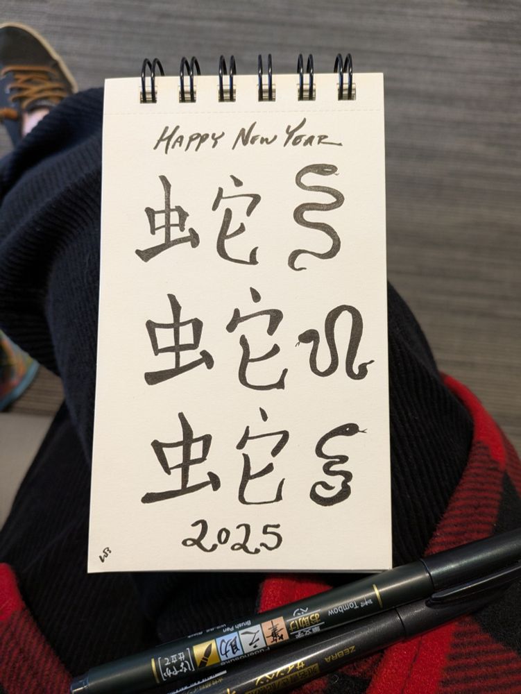 Black ink doodles of snakes and the Chinese symbol for snake, wishing a happy Lunar New Year. 