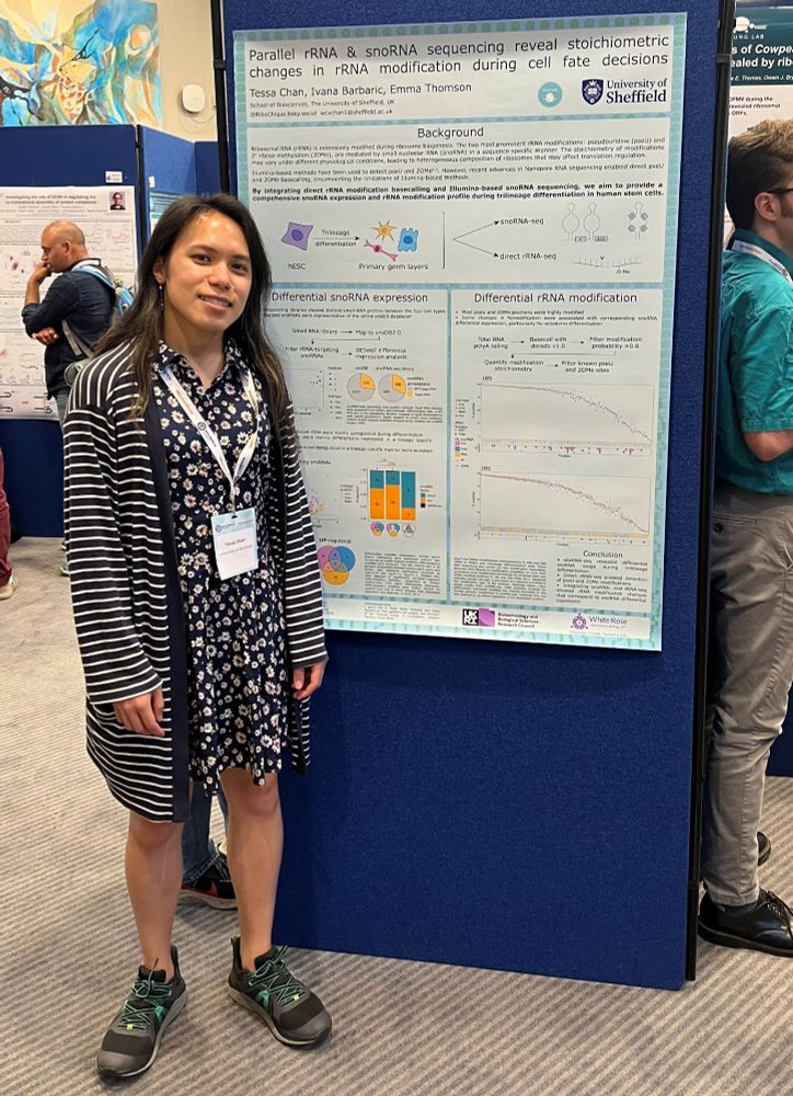 An early career researcher stands beside a scientific poster, displaying graphs and text, at an academic conference.