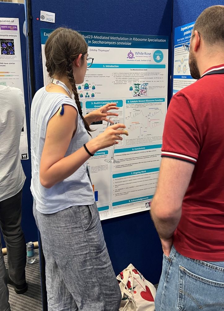 An early career scientist explains their poster to an audience at an academic conference.
