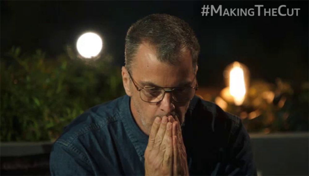 a man wearing glasses is praying with #makingthecut written on the bottom right