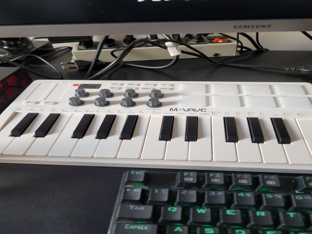 A foto dispõe um teclado controlador midi de 25 teclas, branco, da marca m-wave