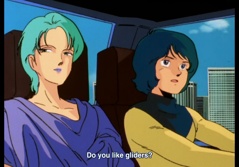 Two blue haired girls in a car, one asks the other “do you like gliders?” 