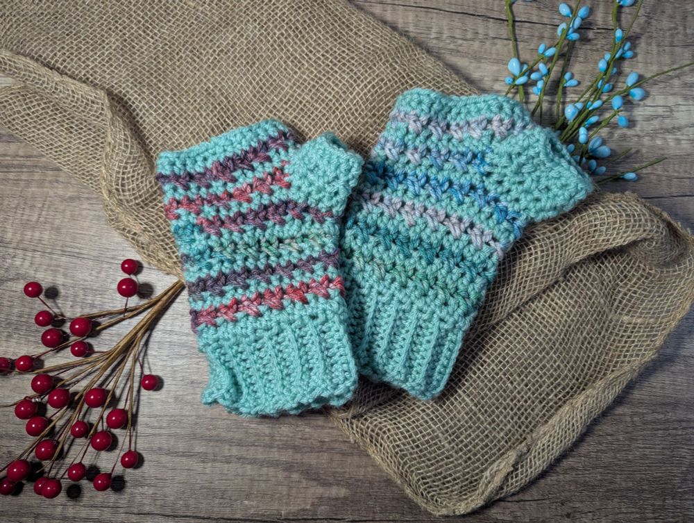 A crocheted pair of fingerless gloves. The gloves are striped with mint and variegated yarn. 