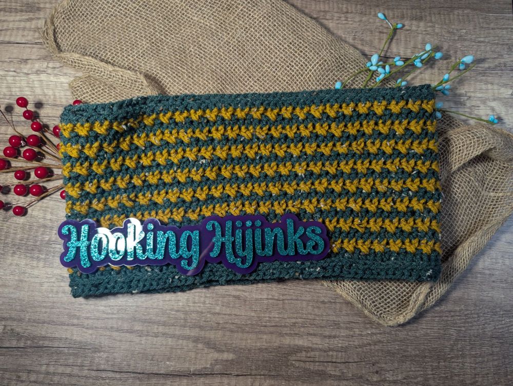 A crocheted cowl. The cowl uses dark green and gold tweed yarns. 