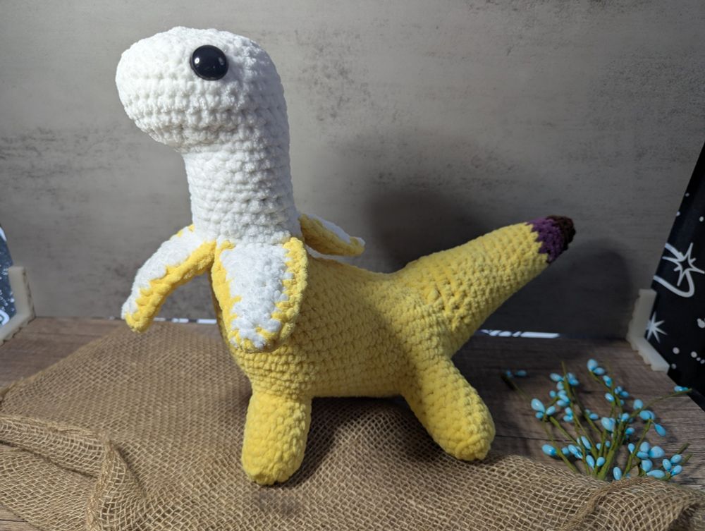 a crocheted toy of a dinosaur that looks like a banana peeled back some