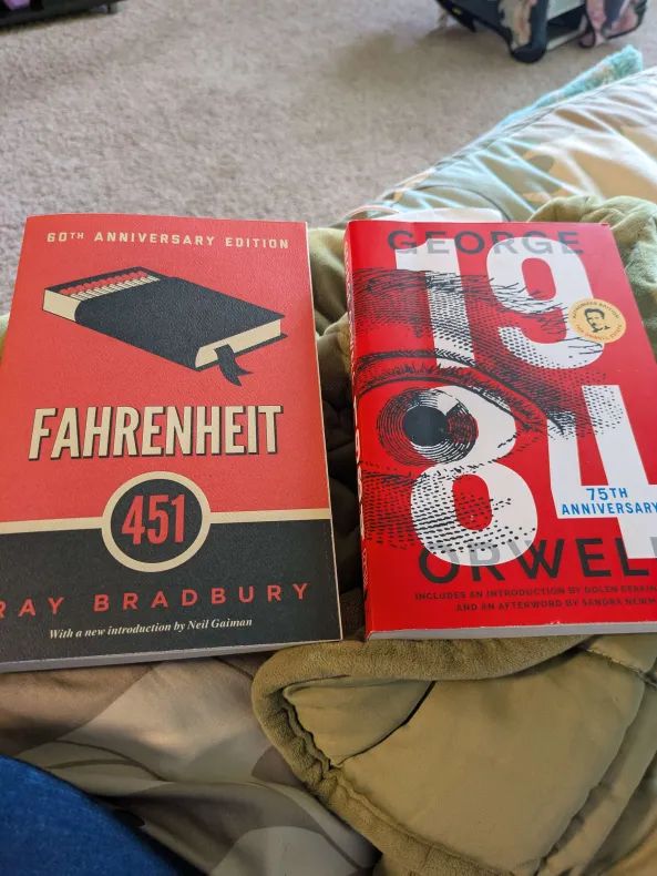 two books side by side. on the left is Fahrenheit 451 by Ray Bradbury, on the right is 1984 by George Orwell. Both cover potential dystopian futures. 