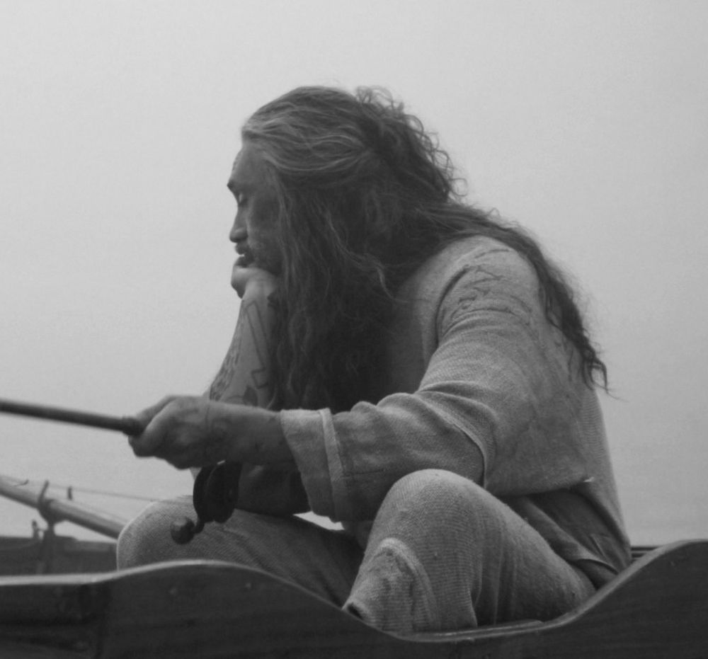 Taika as Ed, doing some fishing, and looking either bored or contemplative.  Possibly contemplating how he's supposed to go to the loo in the onesie.