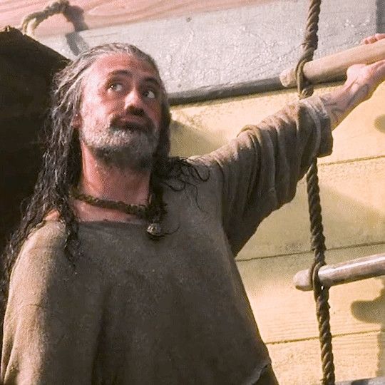 Taika as Ed, hanging off the rope ladder on the side of the ship, making a cartoon face, possibly regretting how itchy the onesie will be as it dries.