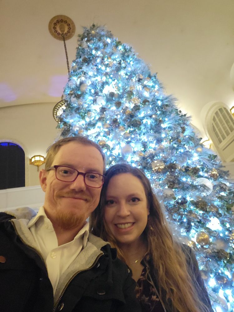 Trent, and his wife, Casey on a date night in downtown Denver on a warm November Friday evening. A large Christmas Tree towers behind them signaling the beginning of consume season.
