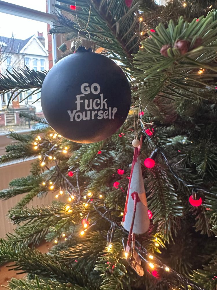 Close up of a decoration hanging on the tree. It says “go fuck yourself”