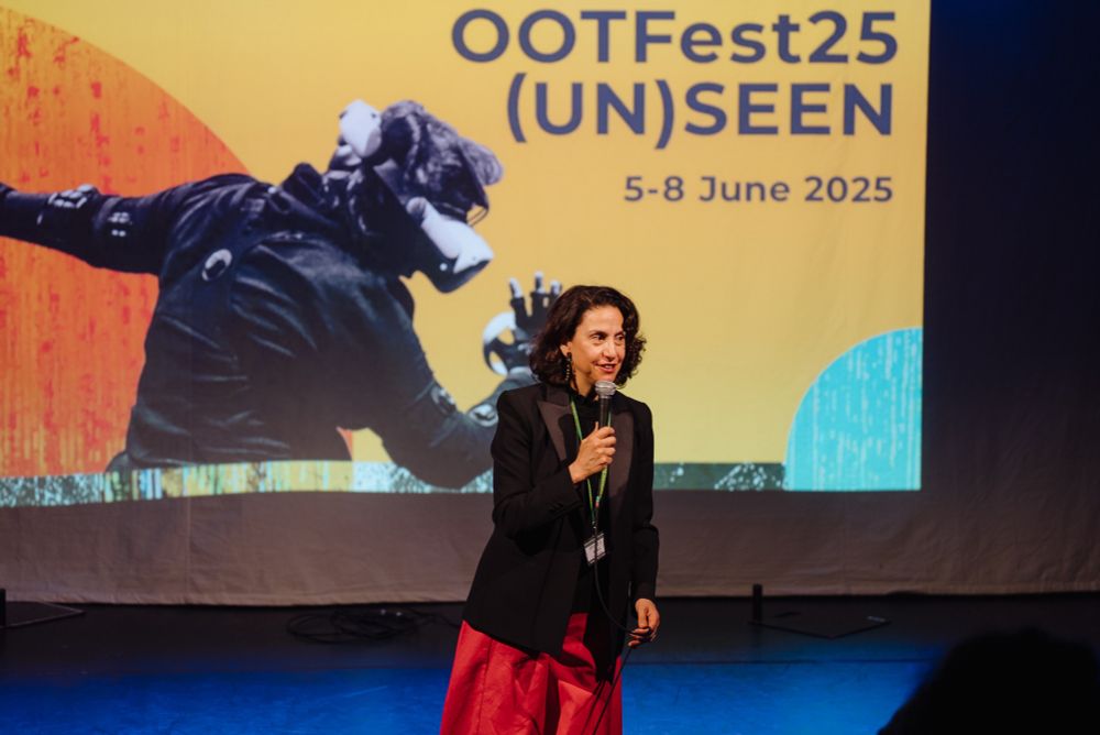 A woman on stage with a microphone to welcome the audience to OOTFest25