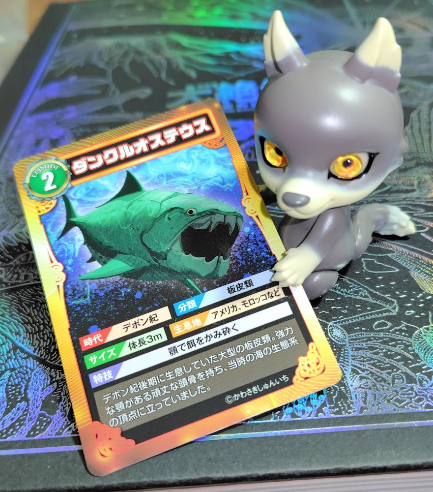 ダンクルオステウスが描かれたトレーディングカード風のカードと、カプセルドールのChestnut Brown