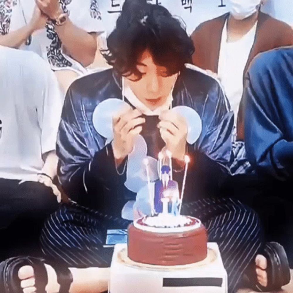 a man wearing a mask is blowing out candles on a cake