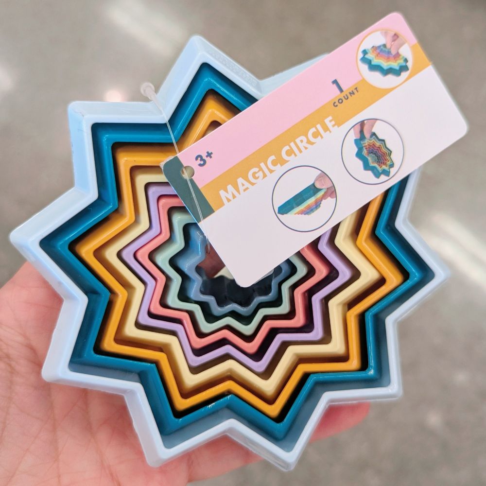 A mulitcolored plastic fidget toy where the pieces nestle inside each other but do not come out and apart, labeled as "magic circle."
