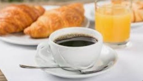 Tasse de café  accompagnée de 2 croissants et d'un jus d’orange 