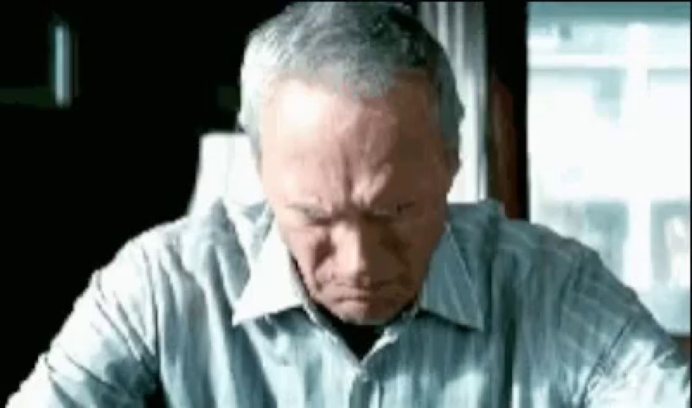 a man in a striped shirt is sitting at a table with his head down .