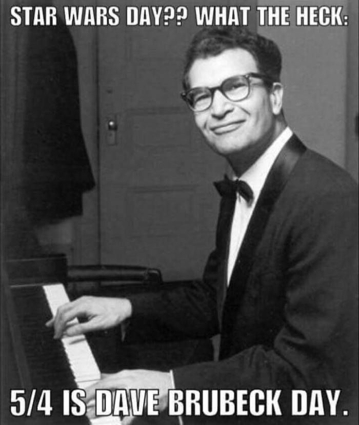 Bild von Dave Brubeck am Klavier, er lächelt verschmitzt in die Kamera. Oben steht in weisser bold Schrift: Star Wars Day?? What the Heck: (und unten am Bildrand gehts weiter mit:) 5/4 is Dave Brubeck Day.