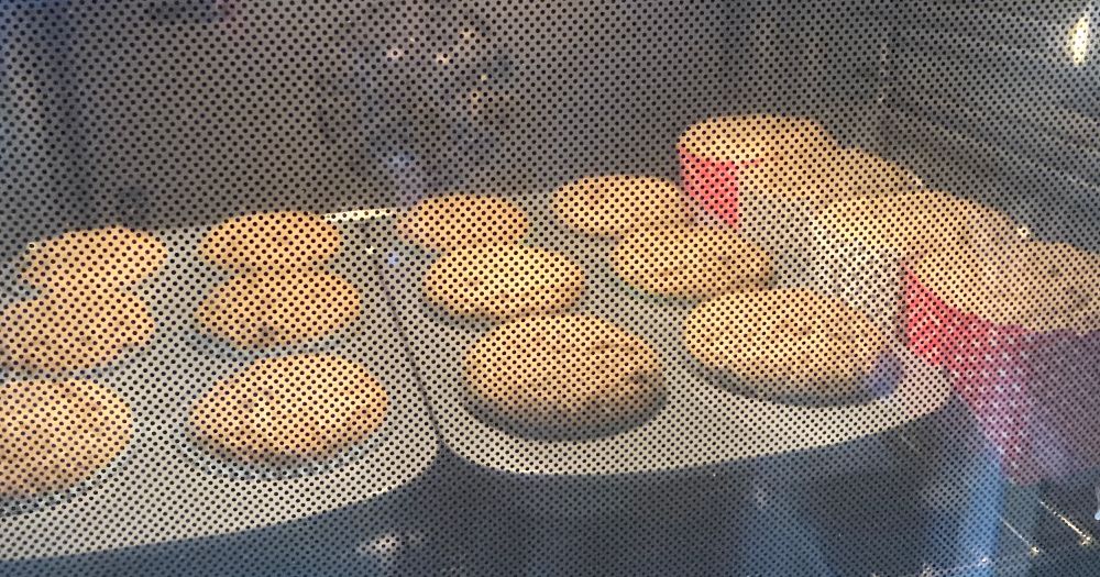 Muffins in Ofen durch schwarzgepunktete Scheibe, etwas aufgegangen 