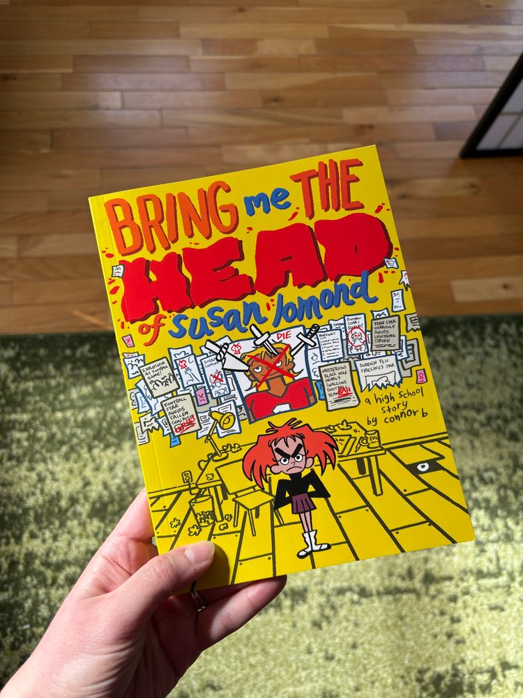 The cover of an indie comic called ‘Bring me the Head of Susan Lomond’ by Connor B. Shows an angry red headed girl in front of a her conspiracy wall of her classmate Susan. 