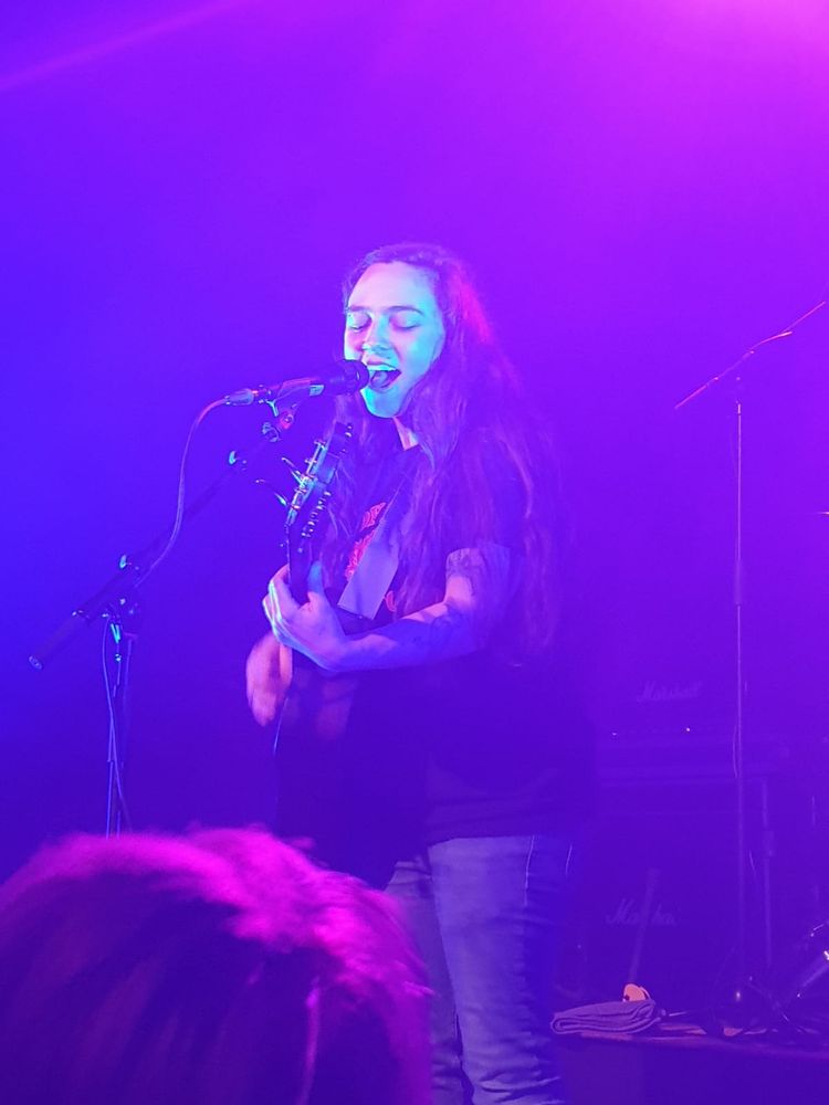 Woman on stage playing a guitar and singing 