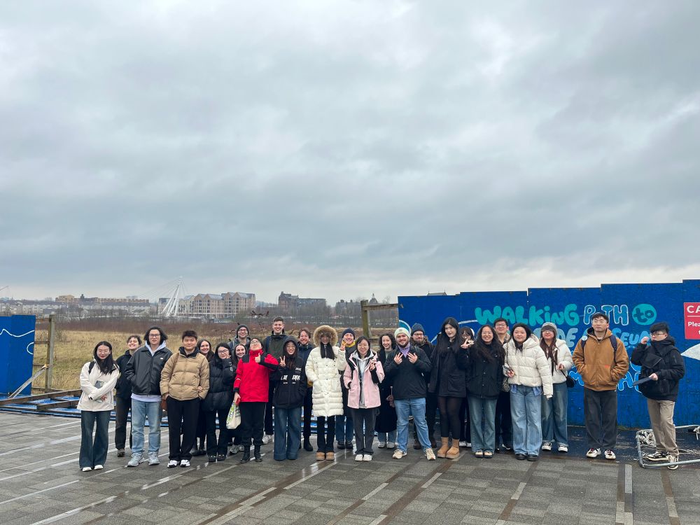 Students standing in front of derelict land with views of Govan 