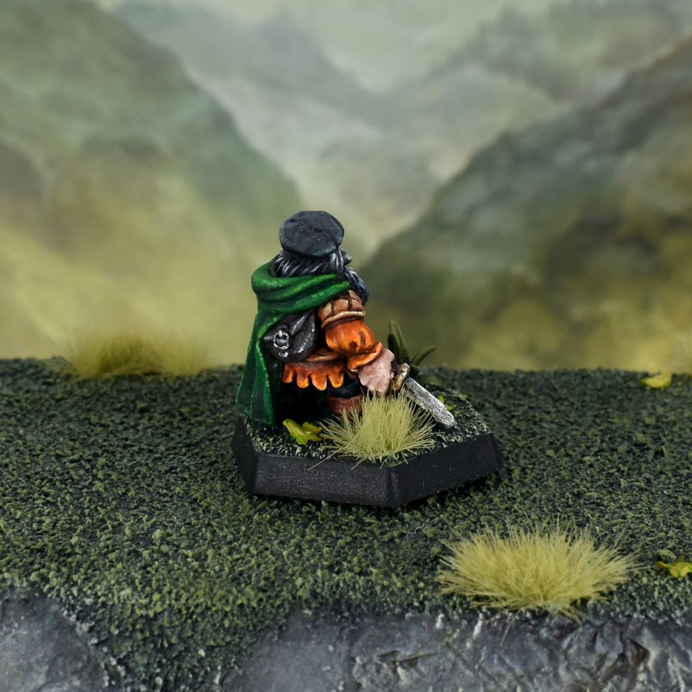 Oldhammer Citadel BC1 "Stealthy Dwarf Thief" with orange tunic, green cloak, grey beard and black beret on a plastic hexagon base.  Rear view.