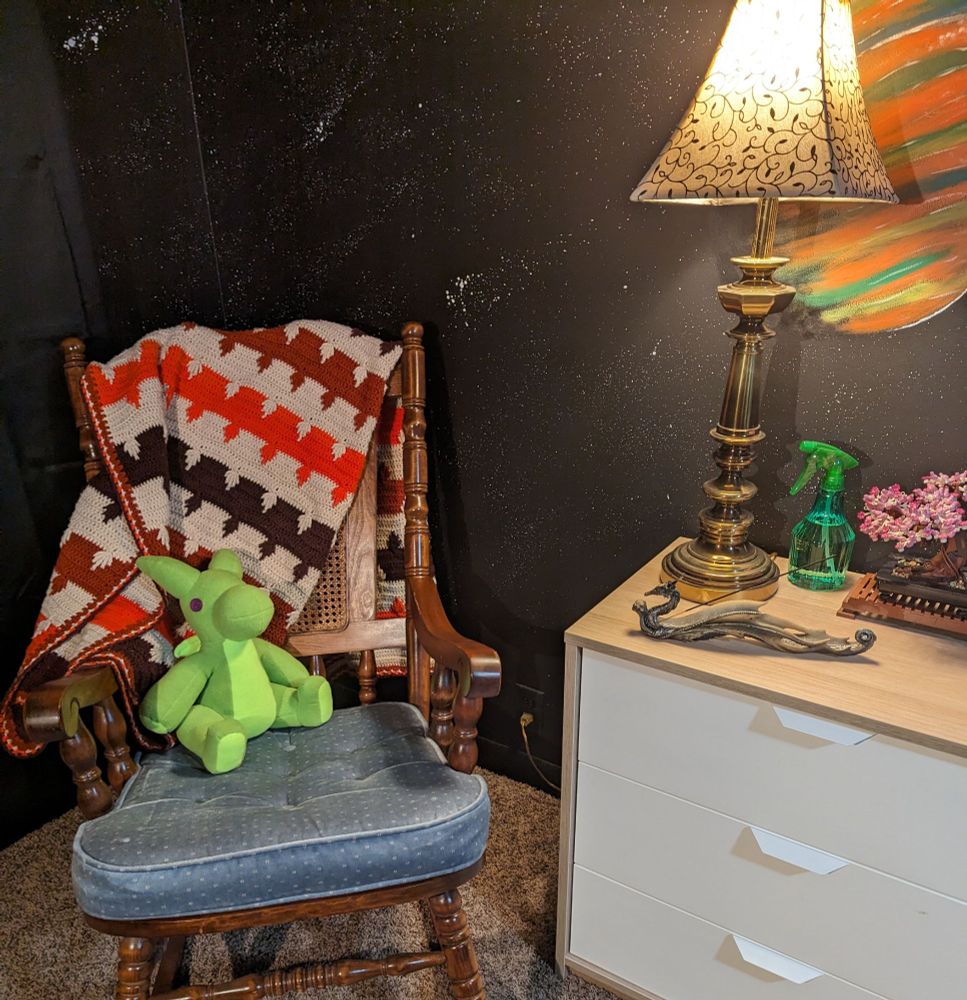A 12 plush green dragon sitting in a wooden rocking chair