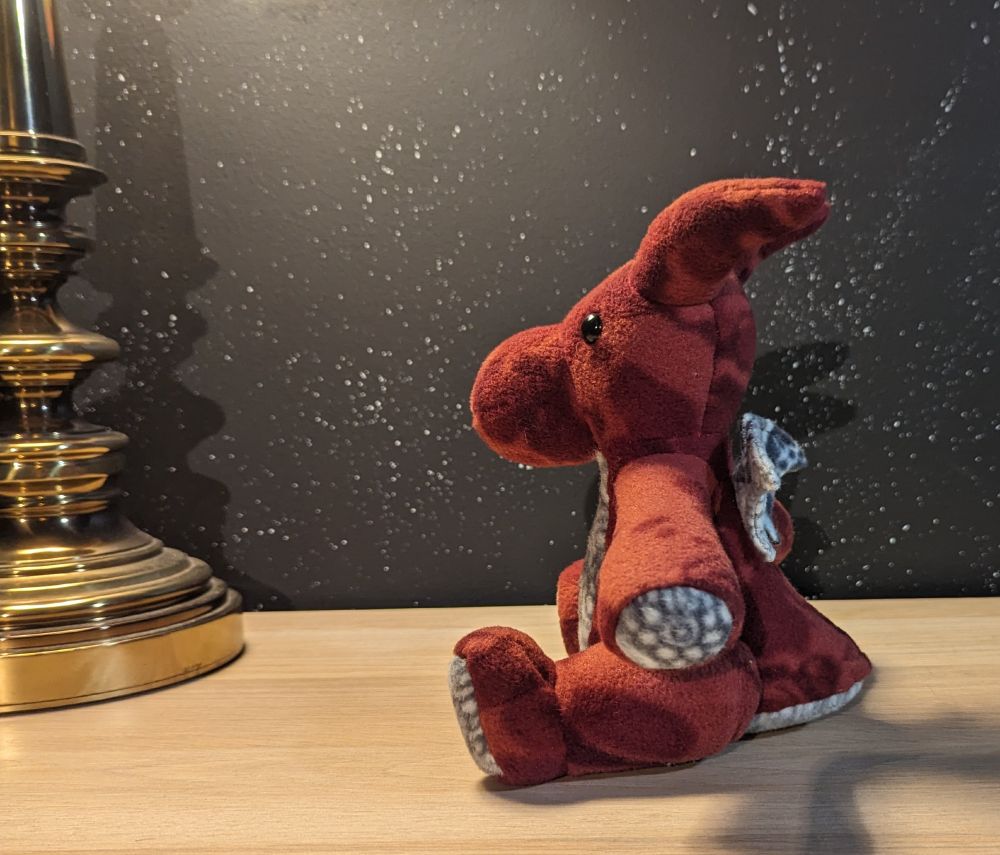 a side view of an 8 inch burgundy and white floral themed plush dragon