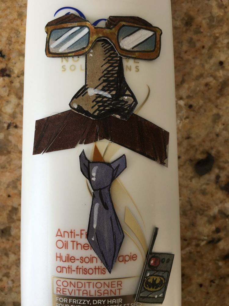 A bottle of hair conditioner with glasses, tie, and mustache. 