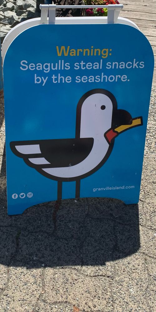 A sign in Vancouver warning customers that seagulls will steal your food. Seagulls steal snacks by the seashore