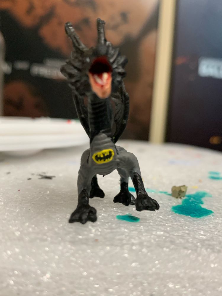 A plastic dragon miniature painted as if wearing a Batman costume