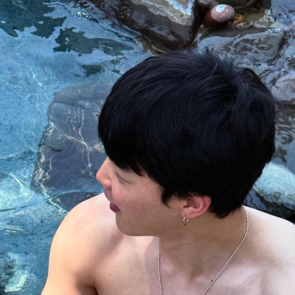 Close up of shirtless Jimin near a pool