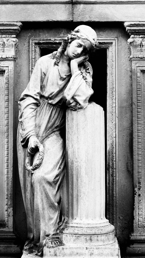 Statue of a sorrowful female figure resting her head on her hand, leaning on a column with a weathered patina, set against an ornate, aged background. Processed in black and white.