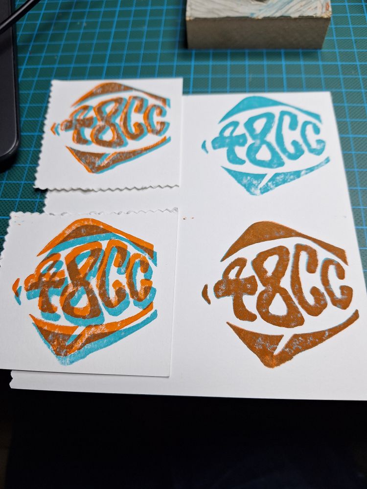 4 impressions en turquoise et orange avec plus ou moins de décalage d'un logo effectué en linogravure