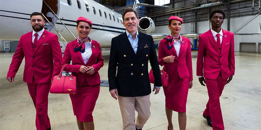 Rob Brydon and four flight crew in front of a private jet. I say 'flight crew'. Could be four RADA graduates.