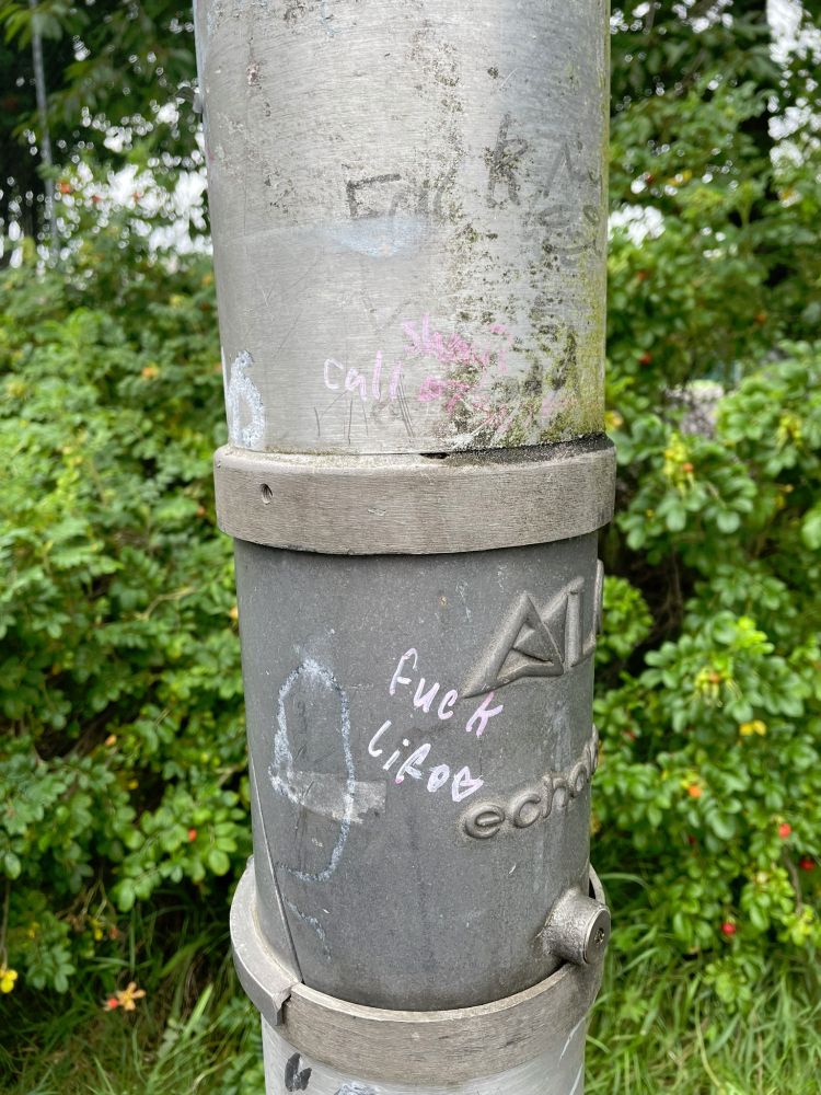 Lamp post with "Fuck life" written on it in pink pen with a love heart.