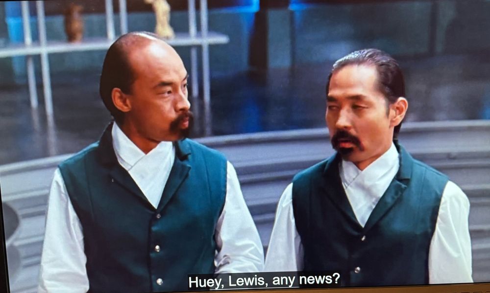 Two henchmen are in frame, confused, being asked “Huey, Lewis, any news?” This is a reference to the seminal band Huey Lewis and the News.