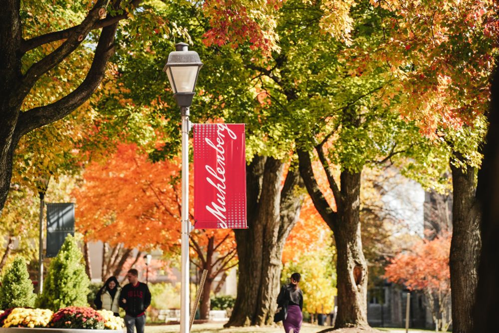 A Muhlenberg banner on a light post with Academic Row in the background.