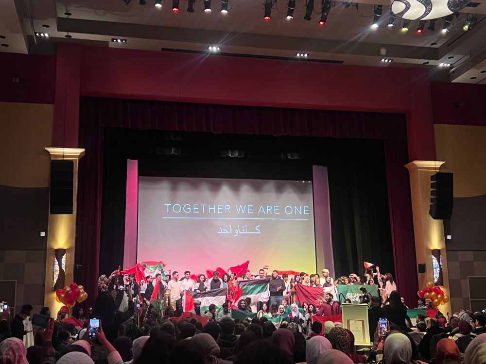 people on stage holding flags of different middle eastern countries and banner that says together we are one.