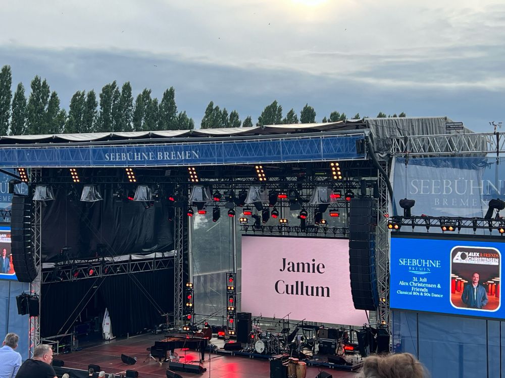 Eine noch leere Bühne mit Instrumenten, im Hintergrund steht "Jamie Cullum" auf einem großen Monitor. Oben an der Bühne steht "Seebühne Bremen".