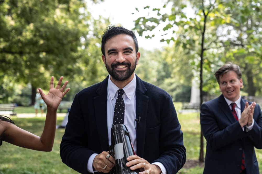 On a cool Sunday in November, a few days after Donald Trump’s re-election, Zohran Mamdani stood on a street corner in Jamaica, Queens, holding up a hastily drawn cardboard sign that read “DID YOU VOTE...