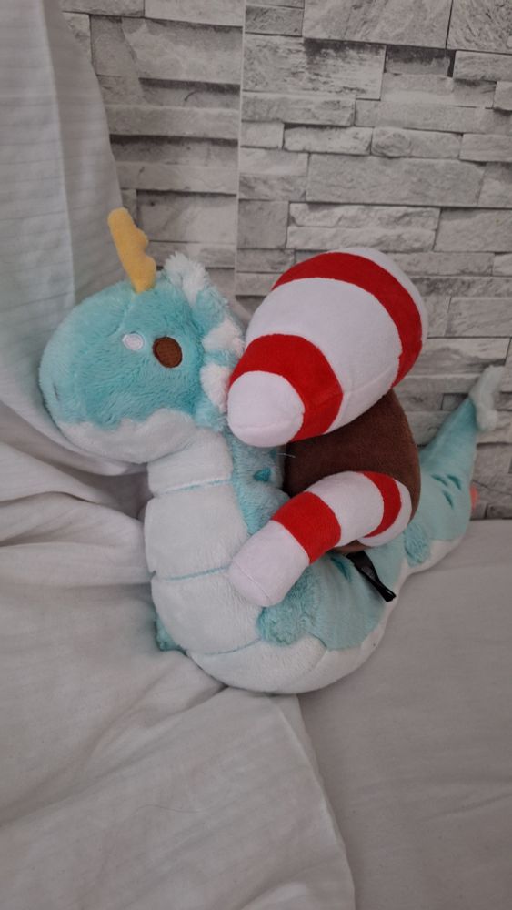 picture of the corrupted Storch plushie sitting on the back of a light blue noodle dragon plushie