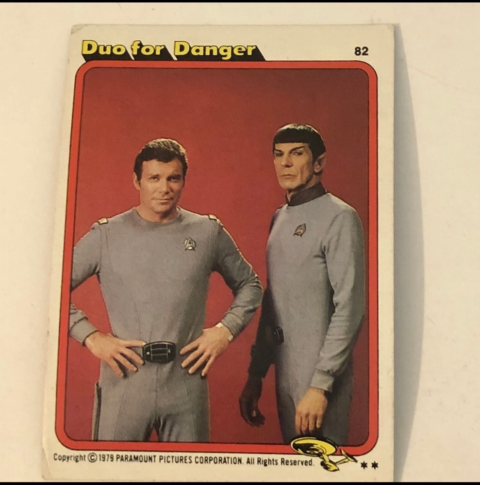 A trading card promoting Star Trek: The Motion Picture. It is inexplicably titled “Duo for Danger” in the upper left corner. It features a photo of Kirk and Spock in their TMP uniforms. Kirk is standing with his hands on his hips, and Spock is standing and his arms just kind of hanging there, hands hovering as if he froze in the middle of moving. They look so awkward. 