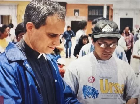 Picture of Pope Leo in Peru —he is wearing a clerical shirt and blue windbreaker and a man is standing next to him.